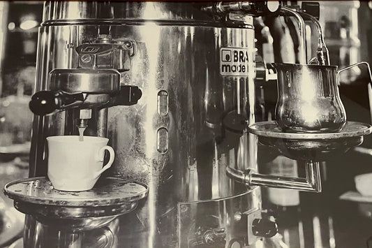 Schwarz-weiß Aufnahme einer klassischen Brasilia Espressomaschine in einem italienischen Café, glänzender Siebträger und Tasse darunter.