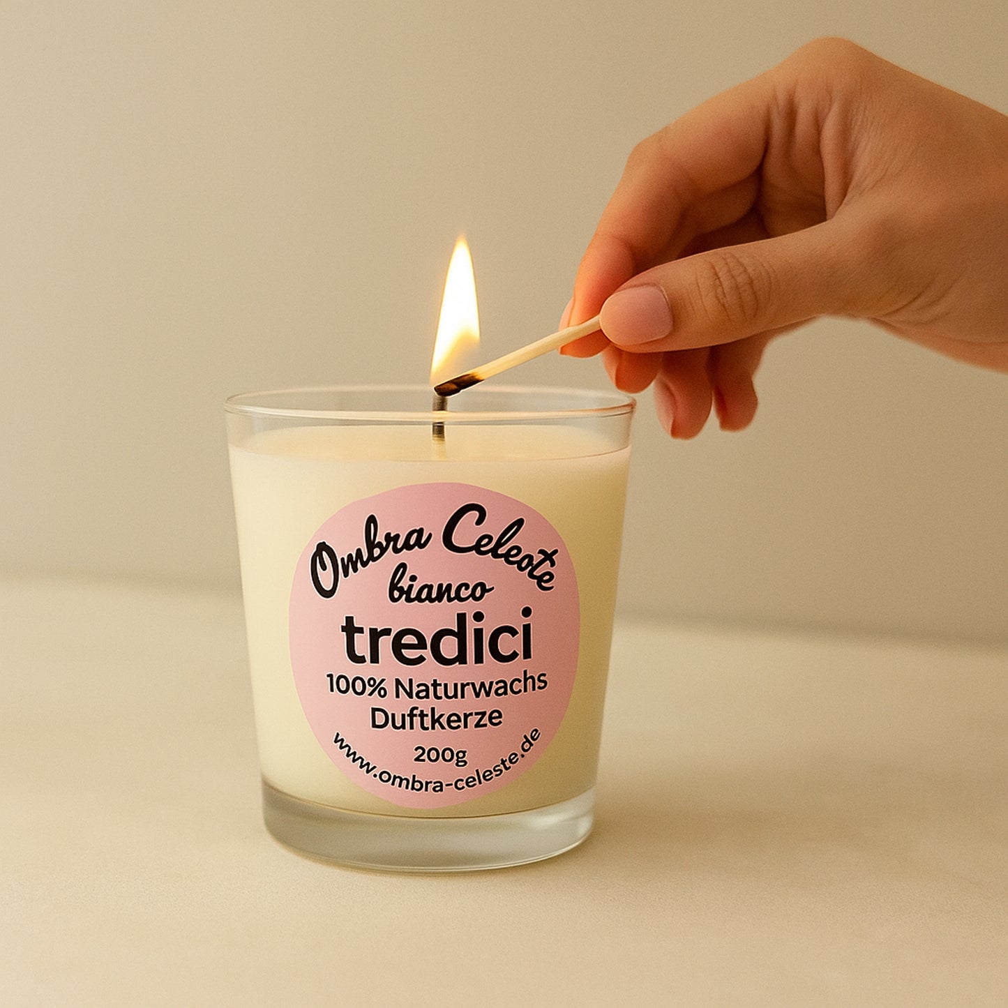 Hand entzündet die tredici bianco Duftkerze von Ombra Celeste, symbolisch für ein achtsames Ritual.