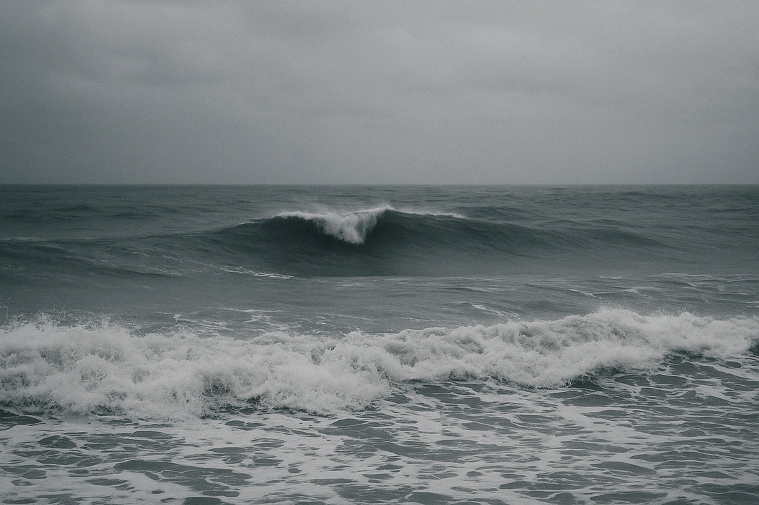 Dramatische Atlantikwellen unter schwerem Himmel, die mit kraftvollen Linien auf die Küste zurollen. Bewegtes, energiegeladenes Meer in kühlen Grau- und Blautönen, atmosphärisch und weit.
