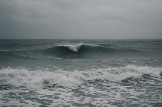 Dramatische Atlantikwellen unter schwerem Himmel, die mit kraftvollen Linien auf die Küste zurollen. Bewegtes, energiegeladenes Meer in kühlen Grau- und Blautönen, atmosphärisch und weit.