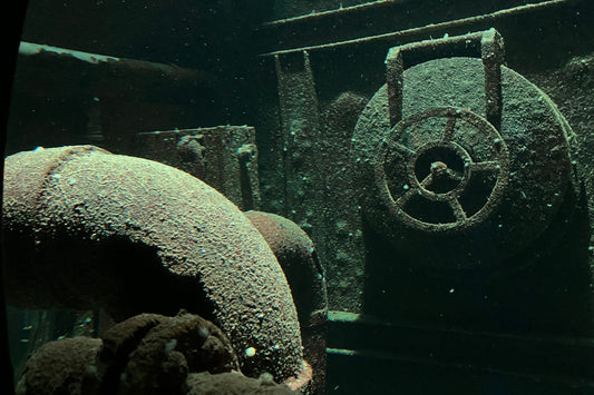 Unterwasseraufnahme eines rostigen Schiffdetails – still, versunken, von Licht durchzogen. Ein Blick in die Tiefe der anderen Welten