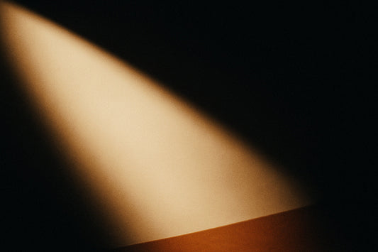 Ein schräger Goldstrahl fällt in tiefes Schwarz und warmes Rotbraun – wie eine Nacht, die nicht dunkel ist, sondern heimlich leuchtet.