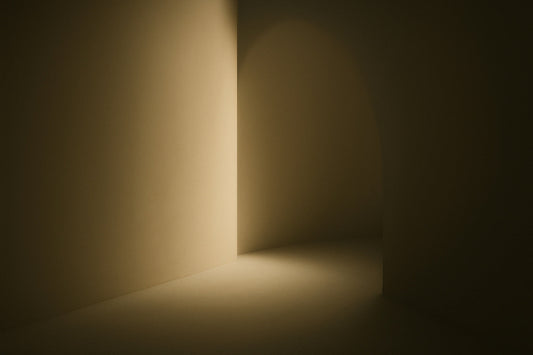 Abstrakter, ruhiger Innenraum mit warmem, diffusem Licht, das wie ein sanfter Atem über Wand und Boden gleitet. Weiche Schatten, minimalistische Linien und ein heller Öffnungspunkt, der wie ein atmender Ort wirkt.