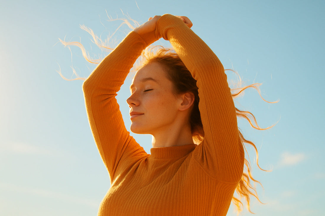 Frau mit ausgebreiteten Armen vor blauem Himmel im goldenen Gegenlicht – Symbol für Freiheit, Leichtigkeit und Freude an der eigenen Gesellschaft.