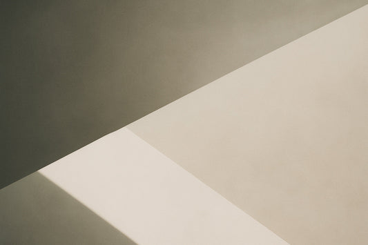 Abstrakte geometrische Komposition mit klarer, diagonaler Lichtkante; oben eine dunklere warmgraue Fläche, unten helle beige Fläche mit präziser Schattenlinie