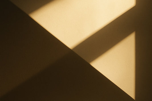 Weiche geometrische Schatten fallen über eine warme beige Fläche und erzeugen eine ruhige, minimalistische Komposition ohne erkennbares Motiv.