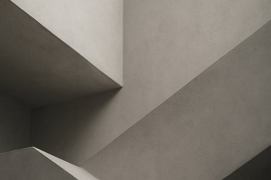 Abstrakte, geometrische Betonflächen überschneiden sich in weichem Licht und erzeugen eine ruhige, minimalistische Komposition ohne erkennbares Motiv.