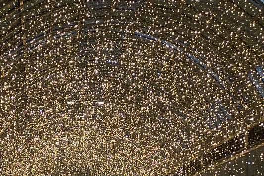 Goldene Lichter unter einer Glaskuppel, geordnet wie ein modernes Firmament. Ein Meer aus Wärmepunkten, das künstlich leuchtet und dennoch etwas Echtes berührt