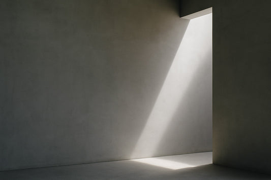 Minimalistische architektonische Innenraumszene: eine große, glatte graue Wand links, rechts eine schmale rechteckige Öffnung, aus der ein präziser diagonaler Lichtstrahl auf Boden und Wand fällt