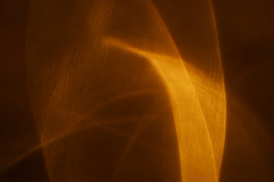 Abstrakte goldene Lichtflächen verschmelzen weich auf dunklem Hintergrund und erzeugen eine ruhige, warme Komposition ohne erkennbares Motiv.