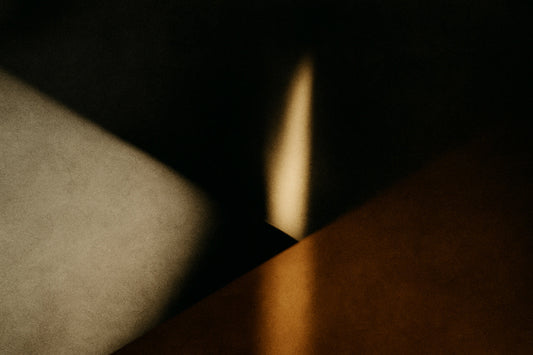 Ein schmaler Lichtkeil fällt in dunkle Tiefe und trifft auf warmes Ocker – wie eine Welt, die sich nicht erklärt und trotzdem sichtbar wird.