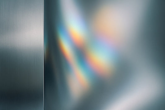 Weiche, kühle Reflexionen auf einer glatten metallischen Oberfläche erzeugen eine abstrakte, minimalistische Stimmung ohne erkennbares Motiv.