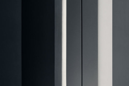 Abstrakte, urbane Architekturkomposition mit drei dunklen vertikalen Flächen; ein schmaler heller Lichtstreifen fällt präzise von oben nach unten und trennt die geometrischen Paneele