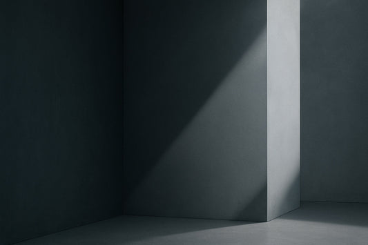 Kühle, minimalistische Architekturszene in Stahlgrau: links eine große, glatte, dunklere Wandfläche, rechts eine helle diagonale Lichtkante, die wie ein präziser Schnitt durch den Raum fällt.