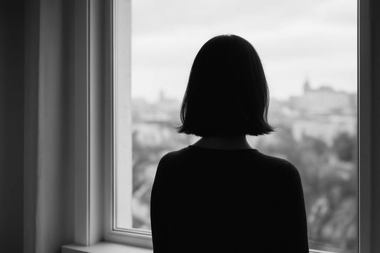 Schwarzweißaufnahme einer Person am Fenster, die still in die Ferne schaut – ein Bild über Wahrnehmung, Ruhe und das Zuhören als Haltung