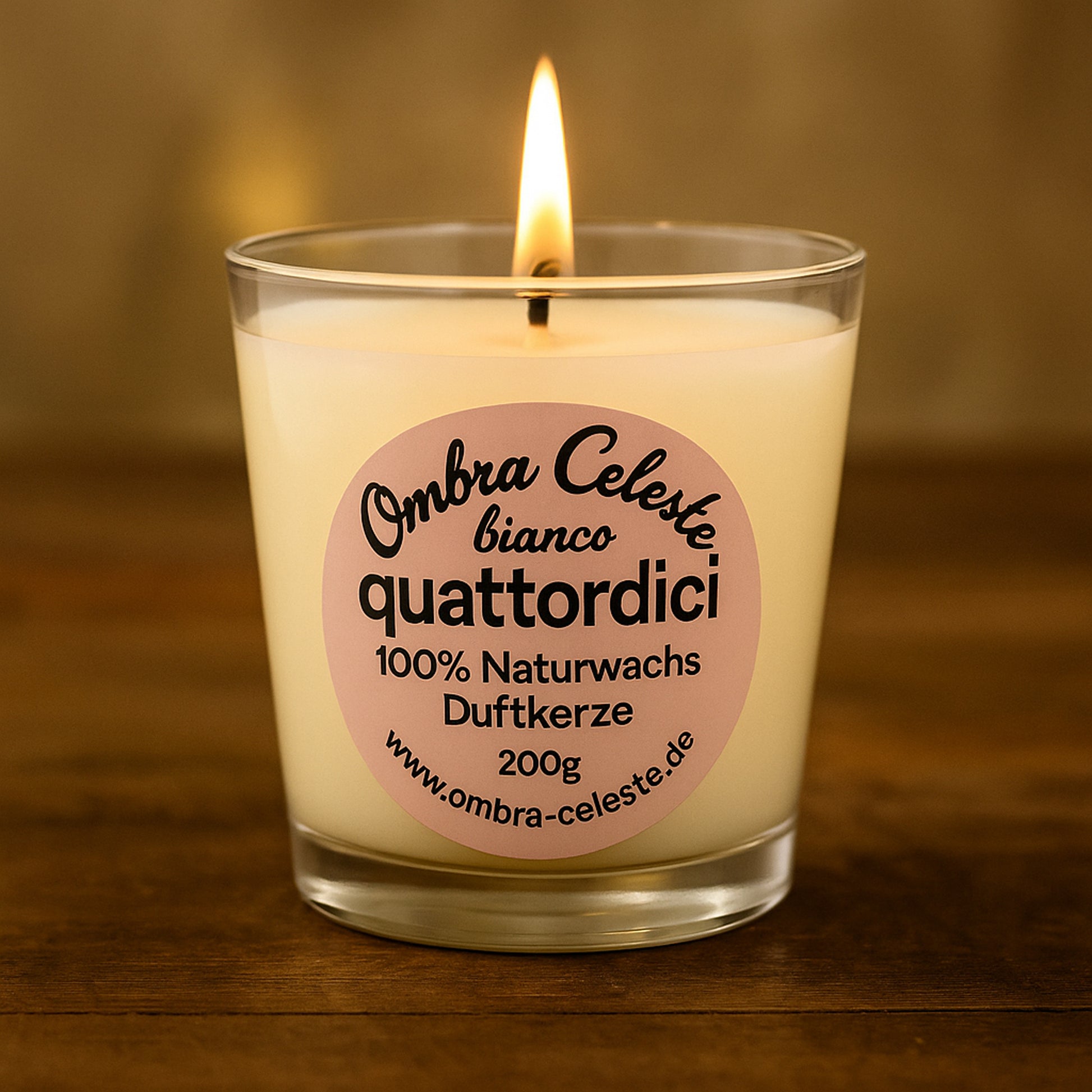 Brennende Duftkerze quattordici bianco auf warmem Holzuntergrund – Etikett in Hellrosa mit schwarzer Schrift, eleganter Lichtreflex im Glas, Fokus auf Flamme und Label.